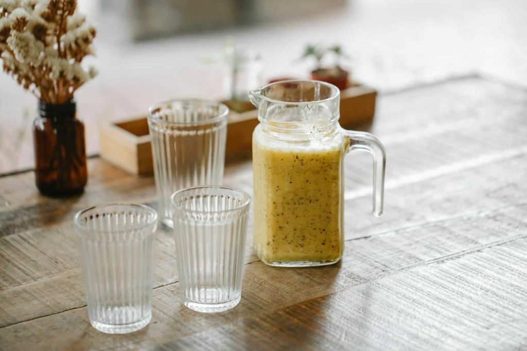 Juice in a jug next to trhee glassess to indicate the differences of Food Processor vs Blender