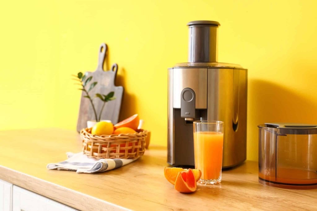 Close up of a juicer close to a freshly made orange juice to showcase the difference Juicer vs blender